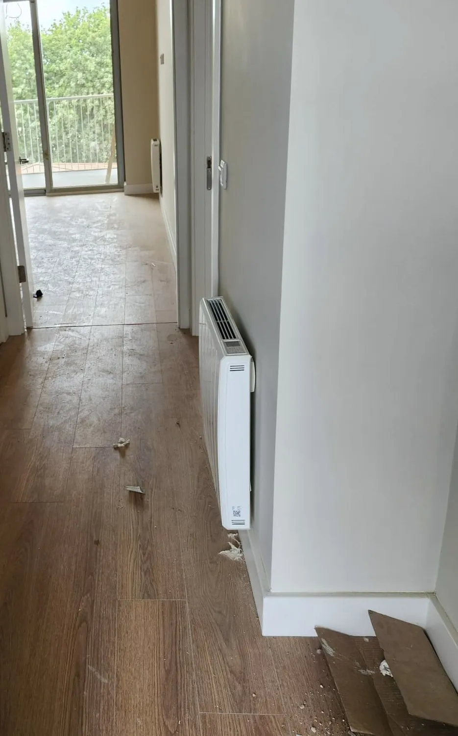 Apartment hallway covered in builders dust, tape and offcuts before cleaning